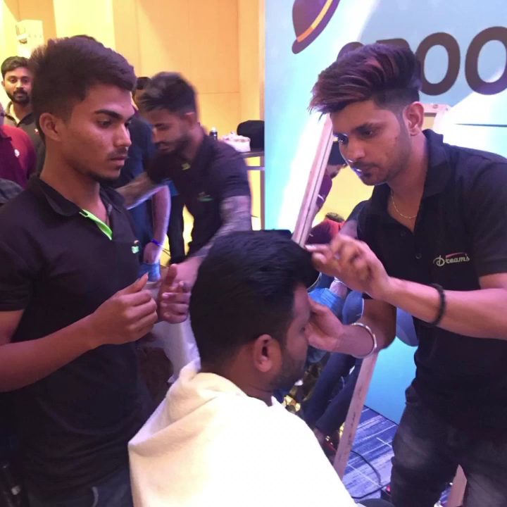 Two Dreams stylists in black uniform finishing a client's cut at the styling station.