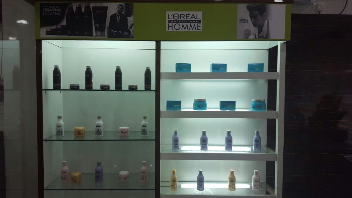 Backlit shelves of L'Oréal Homme men's grooming products at Dreams Men's Salon.