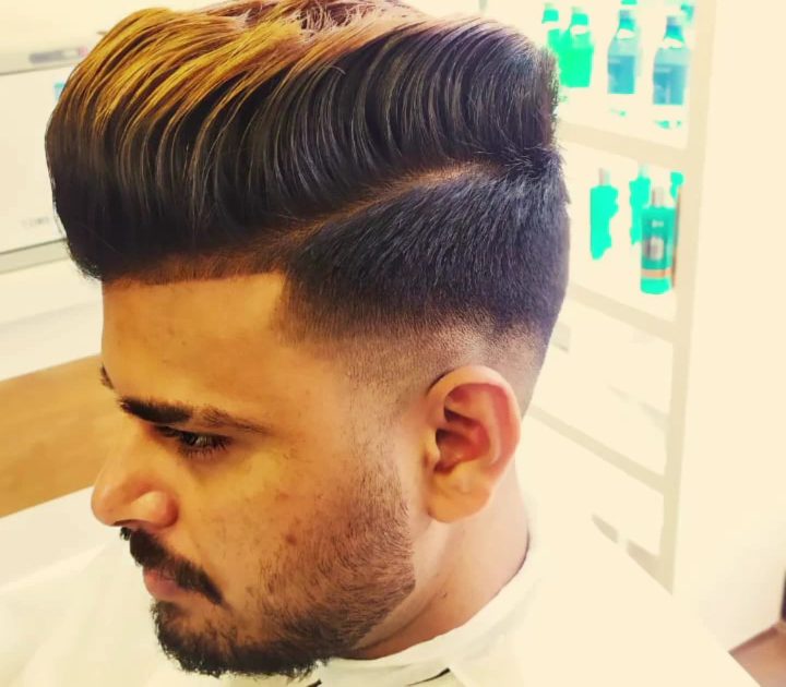 Textured pompadour with a tight skin fade, cut at Dreams Men's Salon Vijayanagar.