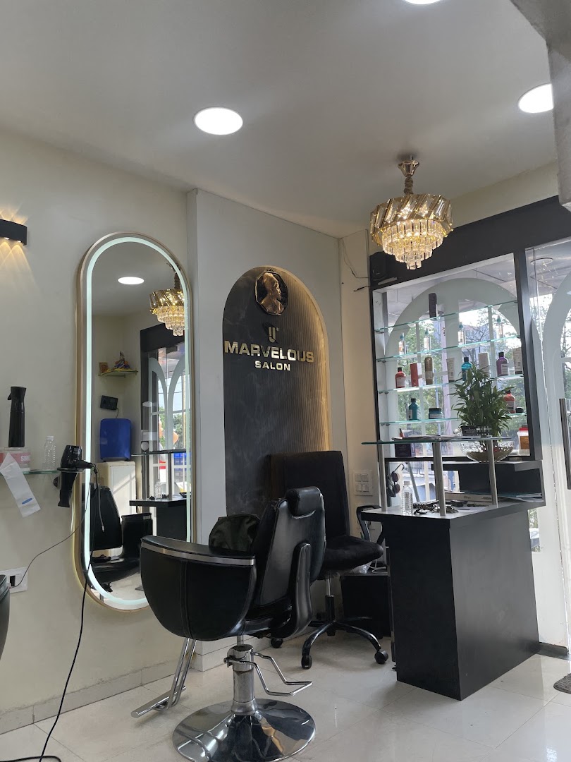 A gold-lit arched mirror and styling chair beneath a chandelier inside Marvelous Unisex Salon