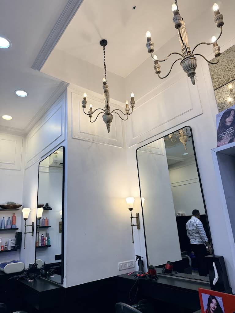 The interior of Salon Muah: white panelling, brass chandeliers and tall mirrors in Pali Hill