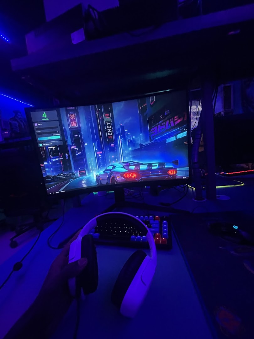 Triple-monitor sim cockpit under neon at TGT