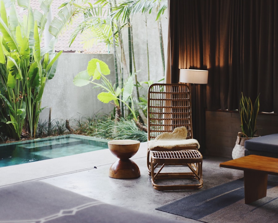 A rattan chair among palms and dark drapes, a lamp glowing warm.